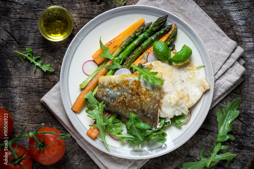 Fish fillet with vegetables on wooden background