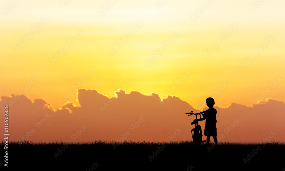 Silhouette of little boy standing hold bicycle sunset background