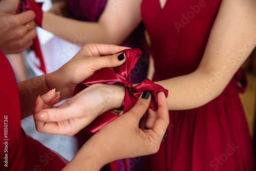 bridesmaids tie a bow at the hands on the wedding day