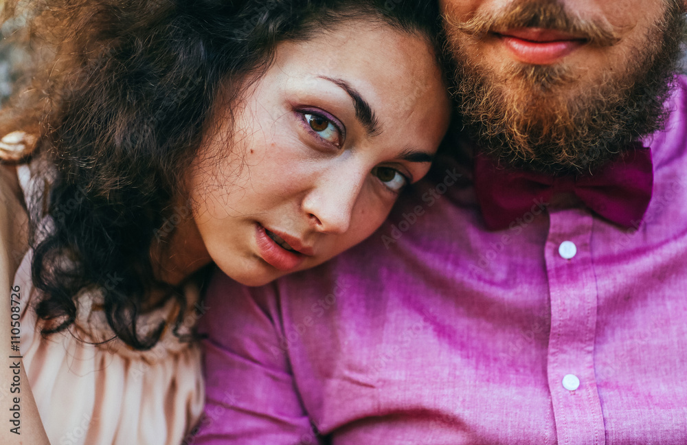 Close up portrait of attractive young couple in outdoor park near old castle. Man with beard, woman with curly hair.