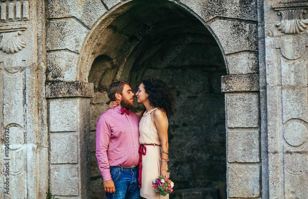 Young couple near old wooden door. Man with beard, woman with curly hair.