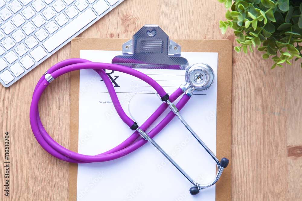 A medical stethoscope near a laptop on a wooden table, on white A medical stethoscope near a laptop on a wooden table, on white