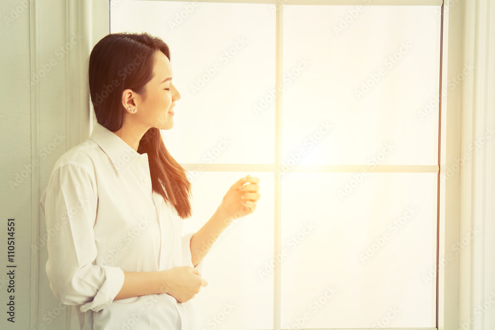 Beautiful young woman looking out in window at home and smiley s Beautiful young woman looking out in window at home and smiley s