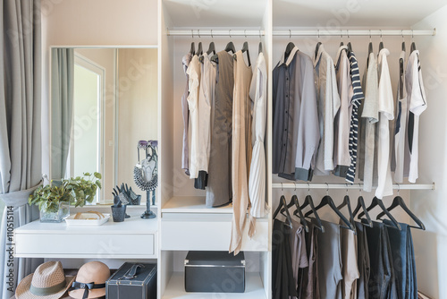 white wardrobe with shirts and pants hanging