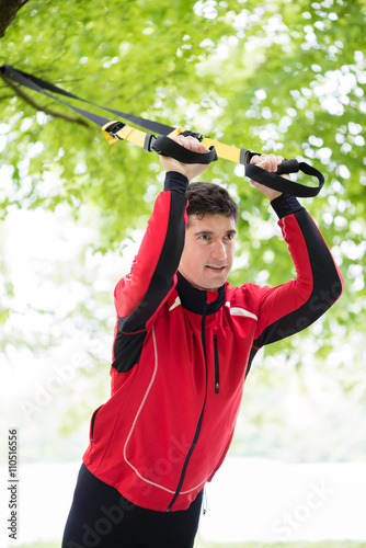 Man doing fitness sling training outdoors