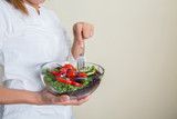 hands of beautiful woman holding big bowl of fresh veggie salad