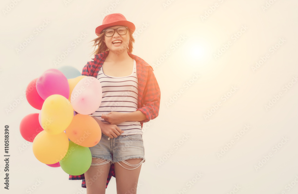 Beautiful hipster woman standing holding balloons on the sand lo Beautiful hipster woman standing holding balloons on the sand lo