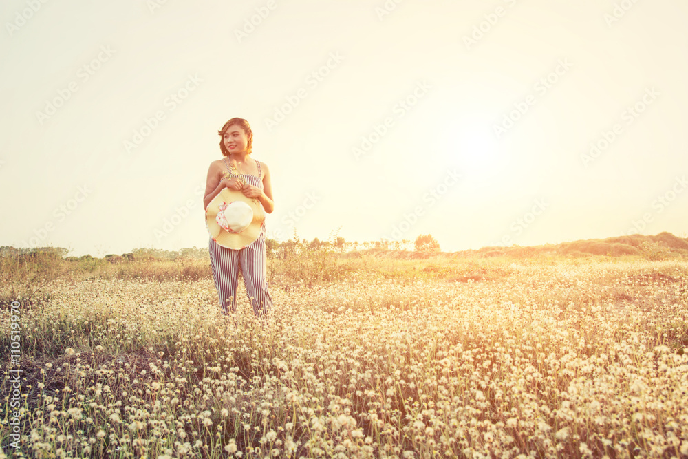 Sexy Beautiful woman standing in flower field and holding her ha