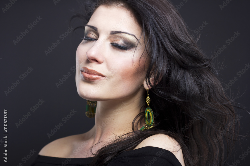 Naklejka premium Beautiful brunette with a flying hair. Portrait of a beautiful girl in the jewelry. Shiny hair. Fashion. Ornaments on the beautiful woman 