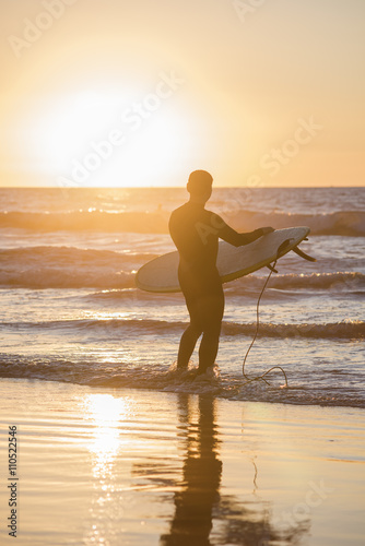 Silhouette of a surfer in front of sun with board during sunset in San Diego  California  with creative flare