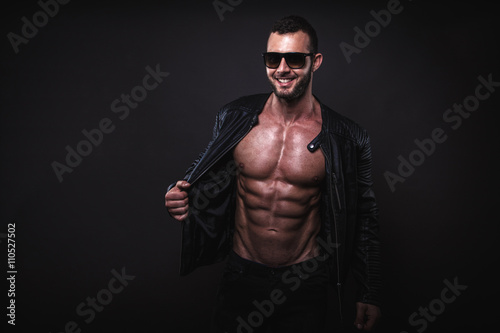 Fit man posing with sunglasses in studio shot.