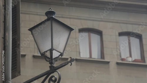 Vintage metal street lamp with ornament fixed on the wall of a building in the old town of Geneve, Switzerland. Windows in the background. photo