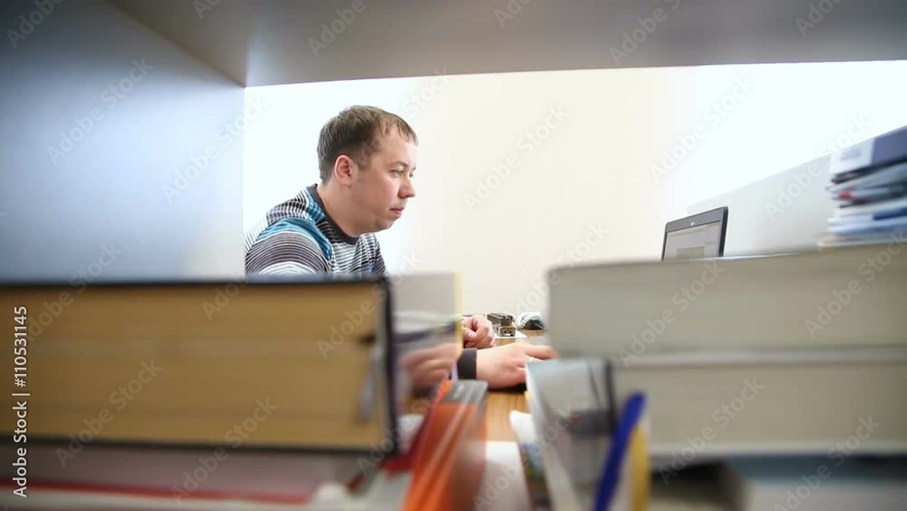 Engineer works at the computer in the background of books and magazines Engineer works at the computer in the background of books and magazines
