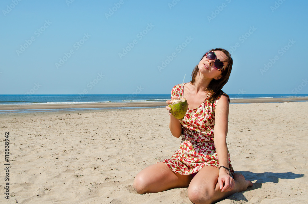 Young woman drinking coconut milk on the beach. Young woman drinking coconut milk on the beach.
