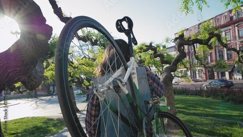 Young hipster man walking and carrying gixed gear bike on his shoulder photo