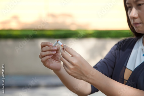 Young beautiful woman holding broken cigarette, people smoke cigarette look like trying to commit suicide, In the day " World No Tobacco Day" please quit or stop smoke for good health.