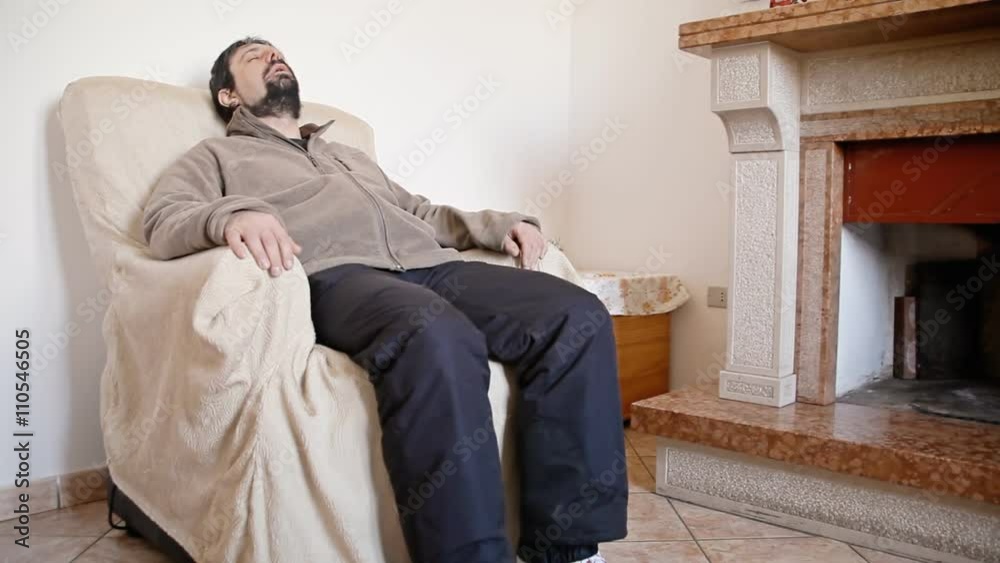A tired man sitting in a comfortable armchair. Winter time.