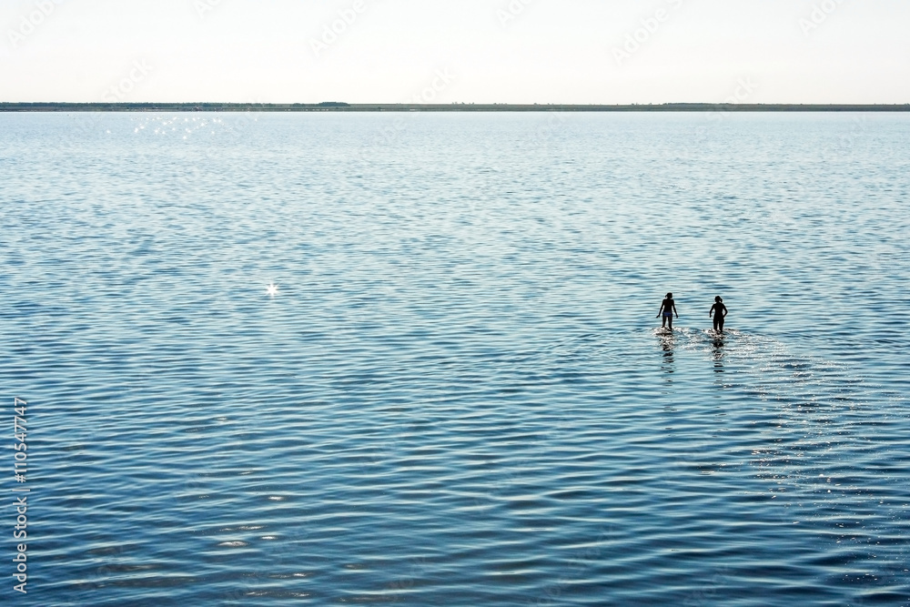 Two women in lake water with reflection