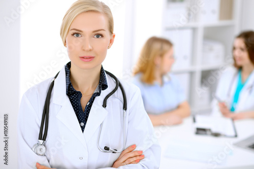 Female doctor smiling on the background with patient and his doctor in hospital