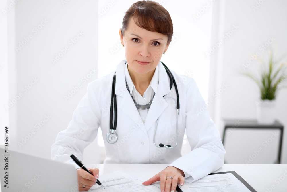Woman doctor filling up medical history at the desk Woman doctor filling up medical history at the desk