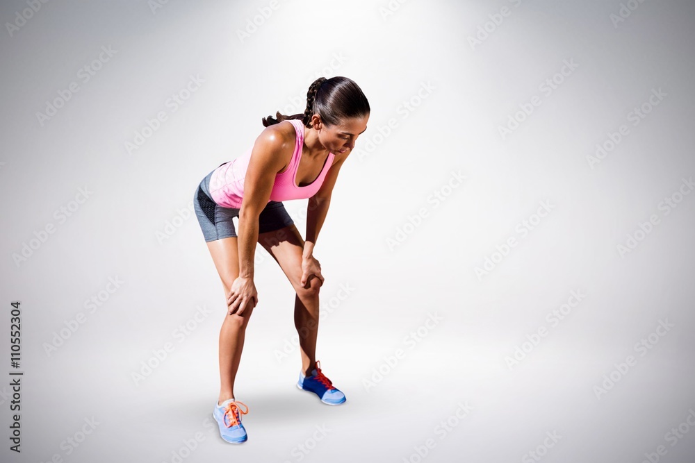 Composite image of athletic woman resting with hands on knees