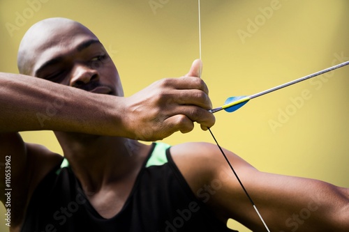 Composite image of close up of man stretching his bow