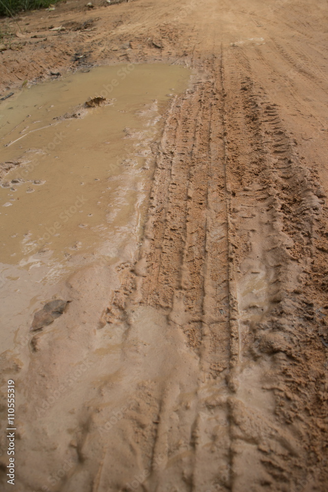 Low angle vertical medium shot of muddy jungle road with soft mud on the left side and fresh tire track. Low angle vertical medium shot of muddy jungle road with soft mud on the left side and fresh tire track.