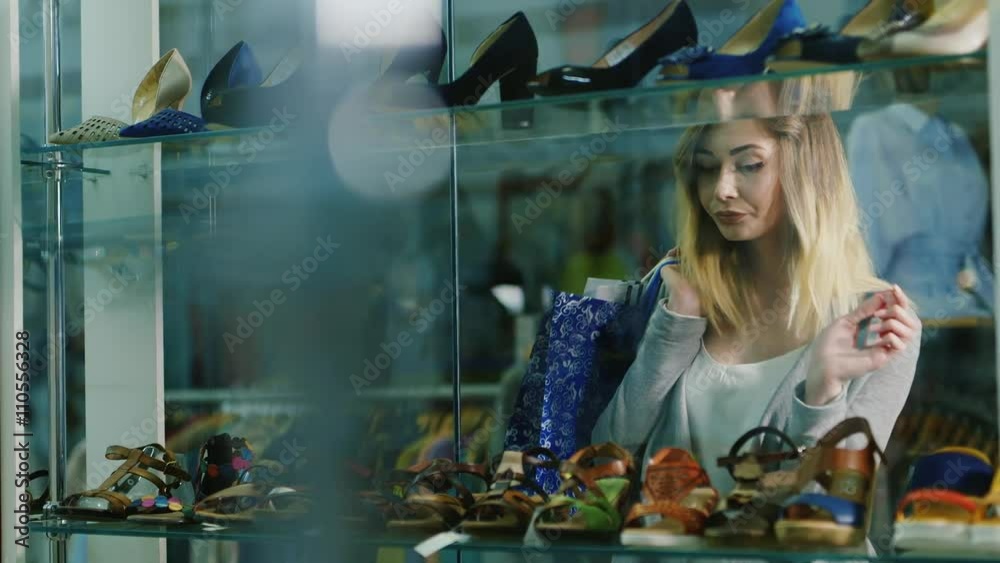 Attractive woman with the card for purchases worth in glass showcases shoe store Attractive woman with the card for purchases worth in glass showcases shoe store