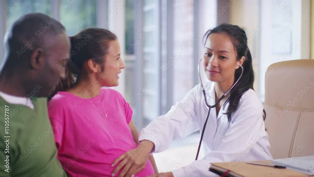 Friendly doctor talking to couple who are expecting a baby Friendly doctor talking to couple who are expecting a baby
