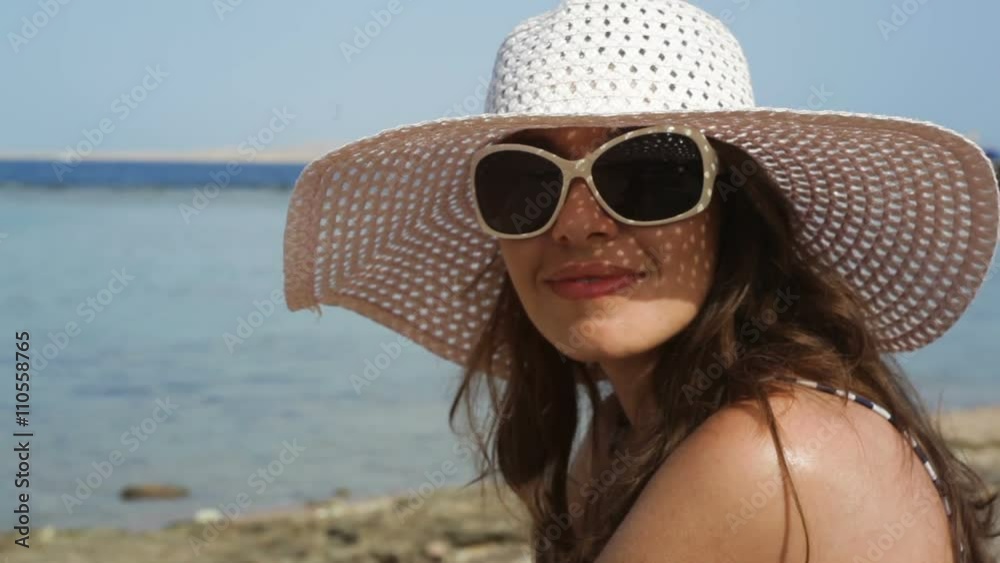 young woman in glasses and a hat on a beach near the sea young woman in glasses and a hat on a beach near the sea