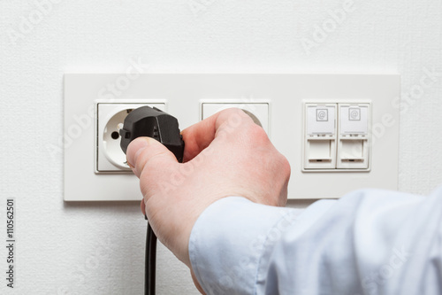 Male hand puts plug in the socket