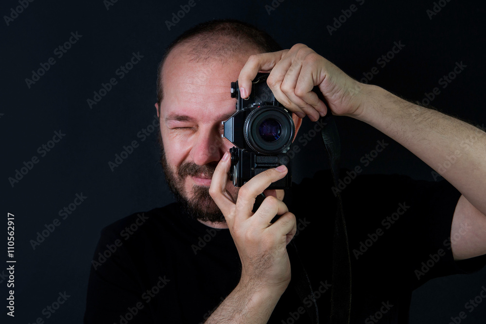 Man on black background in low key, holding analog camera and taking photos Man on black background in low key, holding analog camera and taking photos