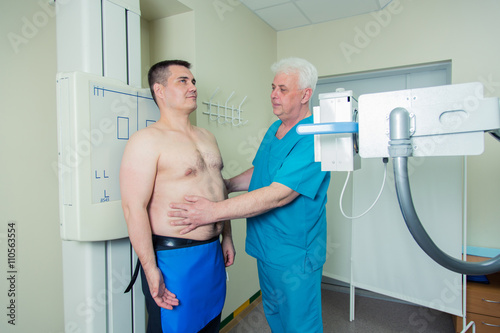 Mid adult man patient  mature male doctor setting up the machine to take x-ray