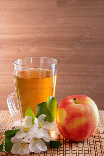Apple juice, apple and apple flowers on a wooden background
