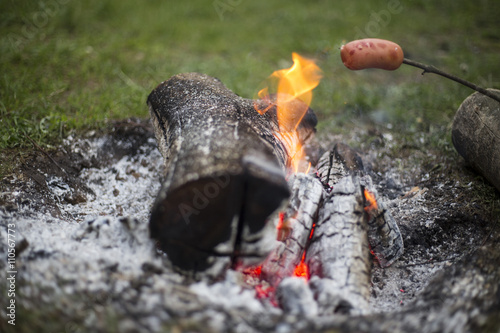 Cooking sausages over a fire.
