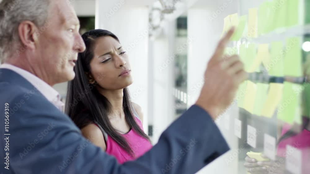 Attractive business man and woman brainstorming for ideas with sticky notes Attractive business man and woman brainstorming for ideas with sticky notes