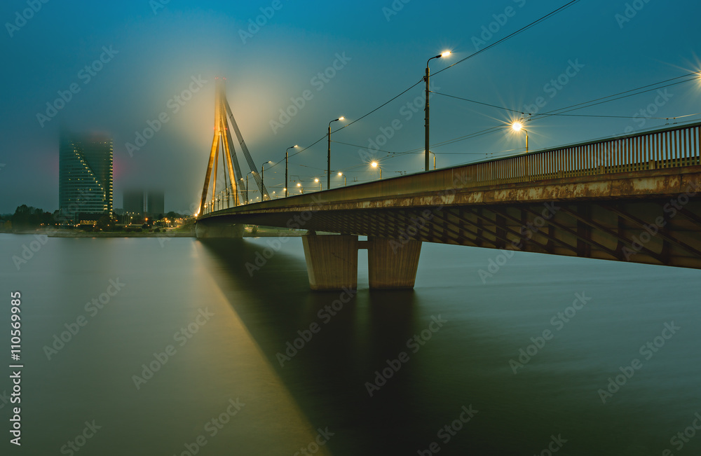 Naklejka premium Cable bridge through the Daugava river in center of Riga - the capital and largest city of Latvia, a major commercial, cultural, historical and financial center of the Baltic region