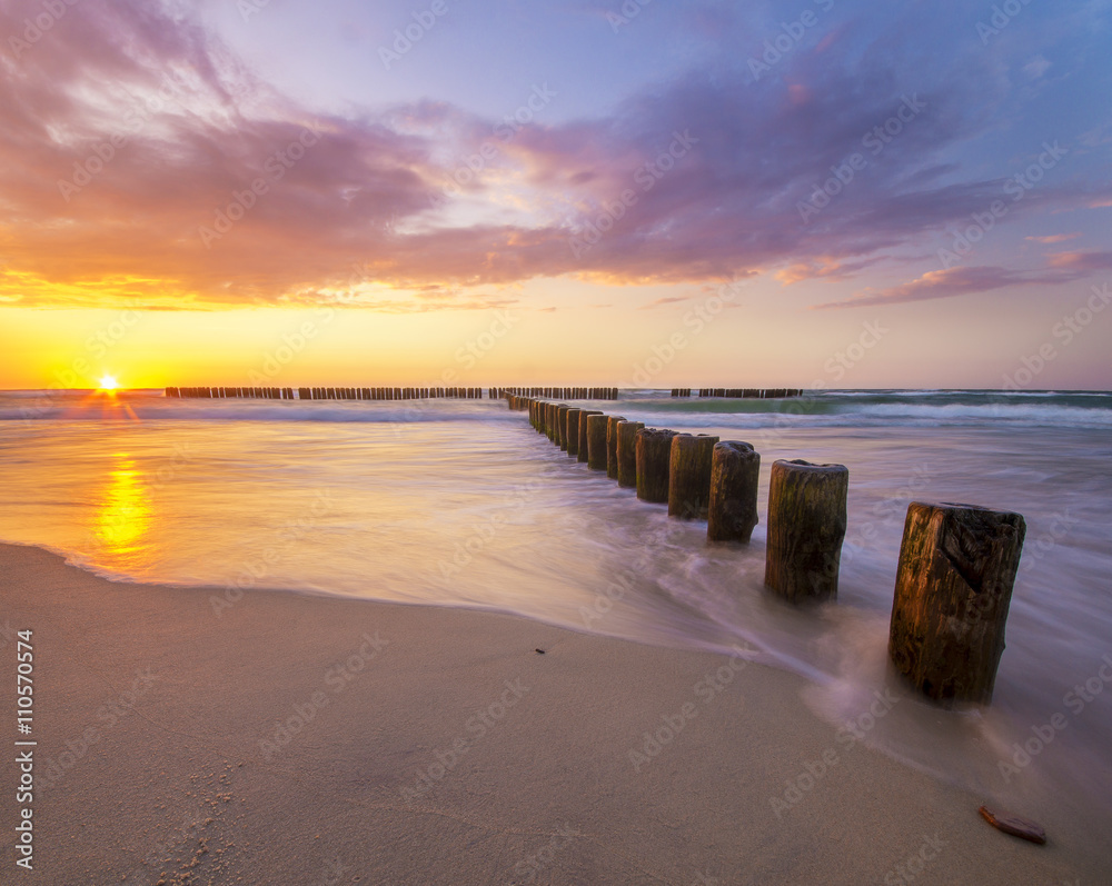 Obraz premium sunset over the sea, beach, beautiful sky and the waves breaking on the breakwater 