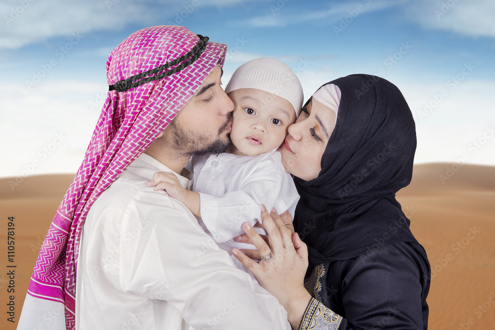 Arabic young couple kiss their son Arabic young couple kiss their son