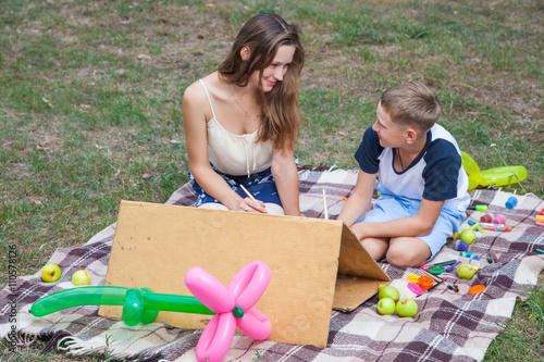 Older sister trying to teach her brother to paint in the park photo