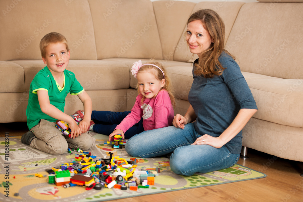Naklejka premium Dzieci i ich mama bawią się klockami na ziemi