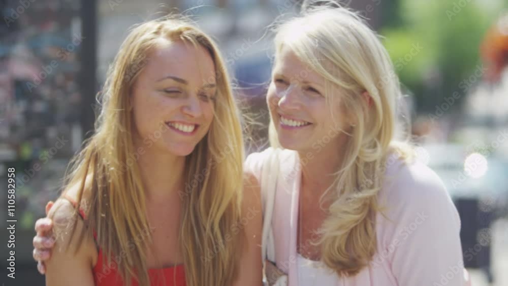 Portrait of beautiful mother & daughter laughing together outdoors in city Portrait of beautiful mother & daughter laughing together outdoors in city