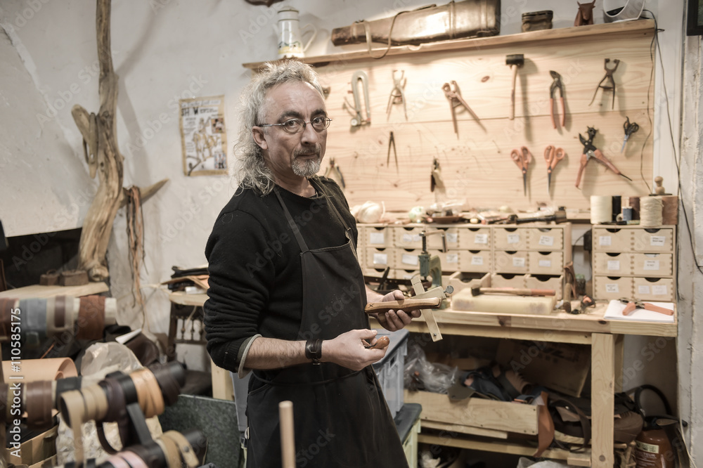 Leather goods craftsman at work in his workshop Leather goods craftsman at work in his workshop