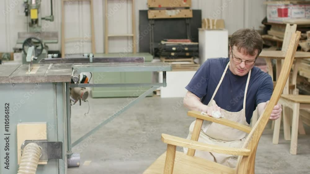 Furniture maker in his workshop, putting finishing touches to a rocking chair Furniture maker in his workshop, putting finishing touches to a rocking chair