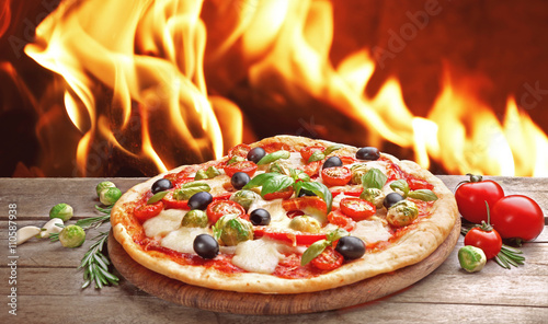 Delicious hot pizza on wooden table against fire flame background