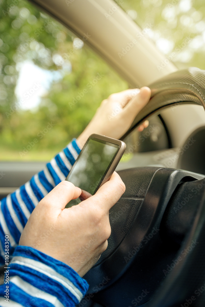 Woman driving car and reading received sms message on smartphone