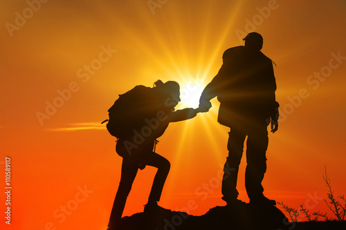 Helping hands with sunlight between two climbers