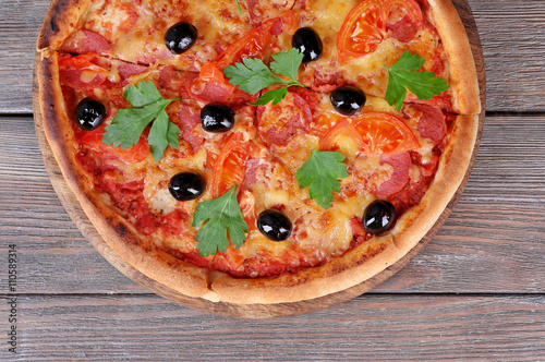 Delicious Italian pizza with black olives on wooden table background