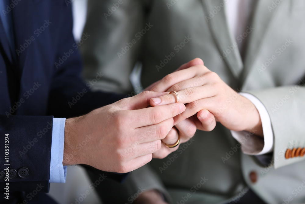 One groom placing the ring on another man's finger