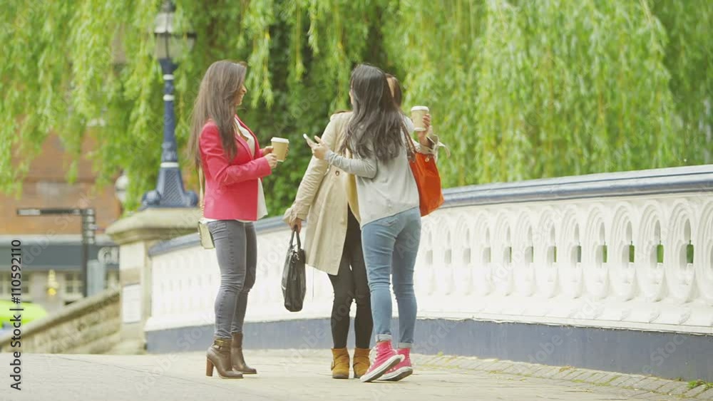 Attractive Asian female friends meet up and greet each other outdoors in the cit Attractive Asian female friends meet up and greet each other outdoors in the cit